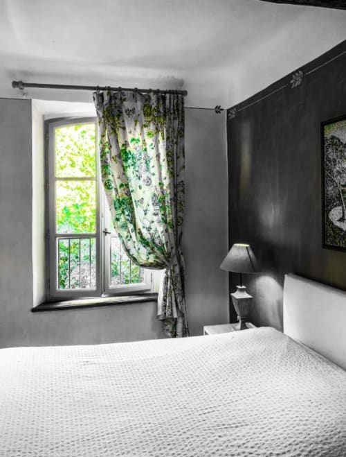 Chambre moderne avec mur d'accent foncé, literie blanche, rideaux aux motifs de feuilles vertes et vue sur la ville à La Cordeline B&B