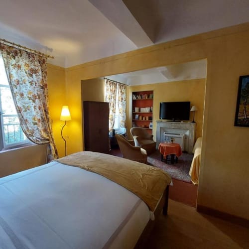 Chambre jaune éclatante à La Cordeline B&B à Brignoles avec armoire miroir, vue sur la ville et coin détente