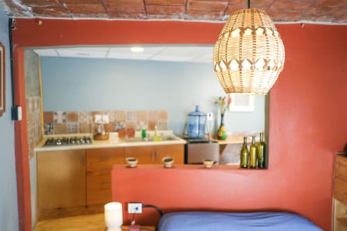 Departamento LLUNA en Oaxaca con lámpara colgante tejida, paredes coral, cocina con detalles azules y muebles de madera