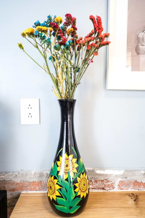 Florero negro con diseño de girasol lleno de flores secas coloridas en el departamento LLUNA en Oaxaca