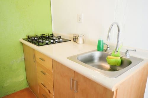 Encimera de la cocina en apartamento LLUNA Oaxaca con estufa de gas, fregadero y pared de acento verde