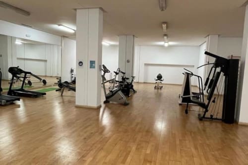 Modern fitness studio with wooden floors, exercise bikes, treadmill, and gym equipment at Marbella Home Rentals Puerto Banús
