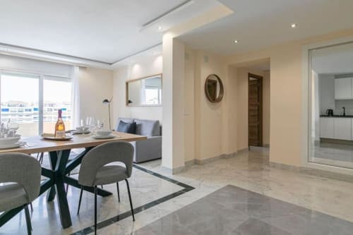 Modern Marbella apartment dining and living area with city views, elegant furnishings, and open kitchen layout in Puerto