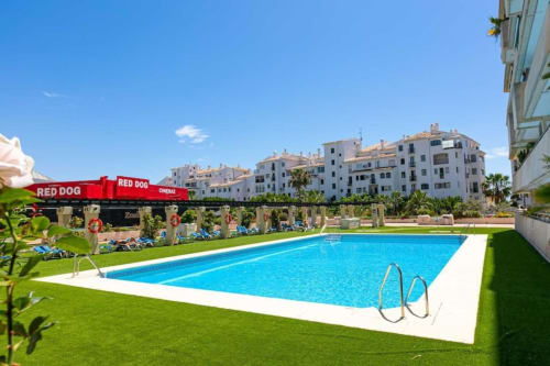 Luxury apartment pool in Marbella with city views, lounge chairs, and palm trees near Puerto Banús