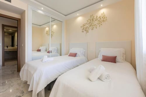 Modern 2-bedroom apartment in Puerto Banús, Marbella with twin beds, mirrored wardrobe, and cream decor