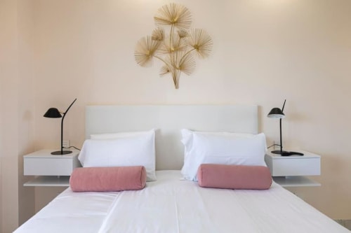 Modern bedroom at Marbella Home Rentals Marina Banús apartment with white bedding, pink bolster pillows, floating