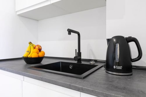 Modern kitchen counter with black sink, faucet, Russell Hobbs kettle, and bowl of fresh fruit in Marbella apartment