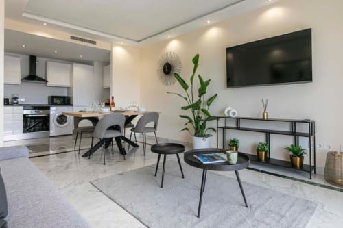 Modern Marina Banús apartment living room with dining area, kitchen, flat-screen TV, plants, and contemporary furnishings in