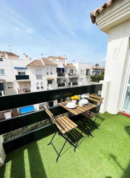 Marbella apartment balcony with dining table, artificial turf, and white residential buildings in Nueva Andalucía
