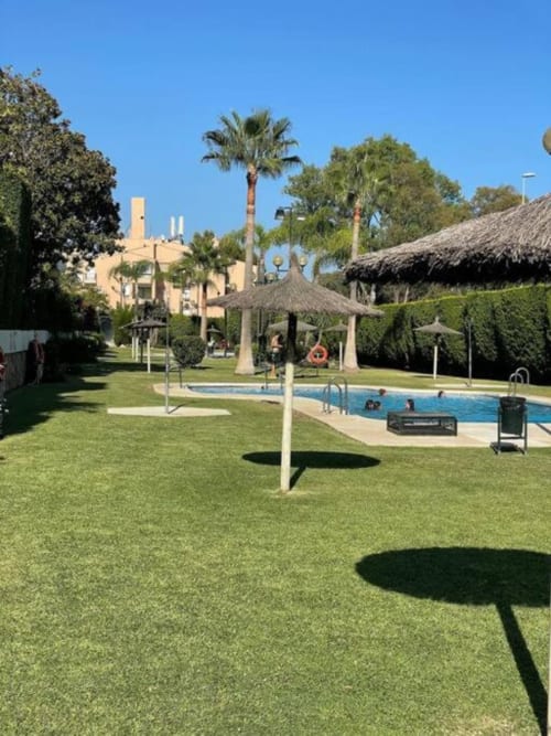 Marbella garden view apartment with swimming pool, palm trees, and manicured lawns in Nueva Andalucía