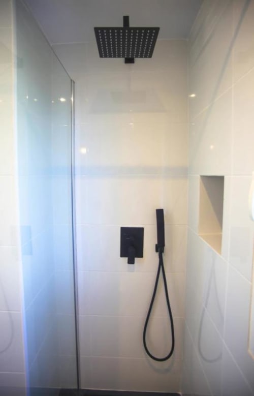 Modern black shower fixtures in white tiled bathroom at Marbella Home Rentals apartment in Nueva Andalucía