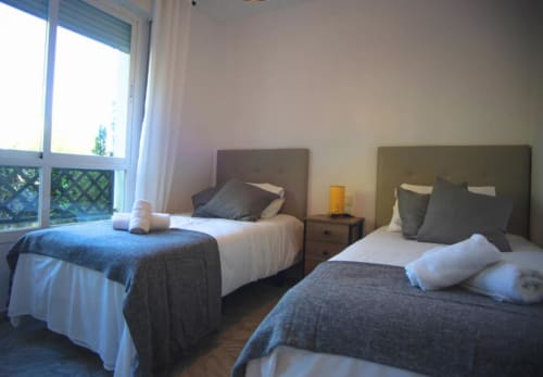 Twin bedroom in Marbella apartment with two single beds, window view, nightstands, and modern décor