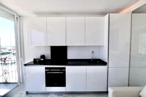 Modern white kitchen with black countertop and appliances in Marbella apartment with sea view balcony access