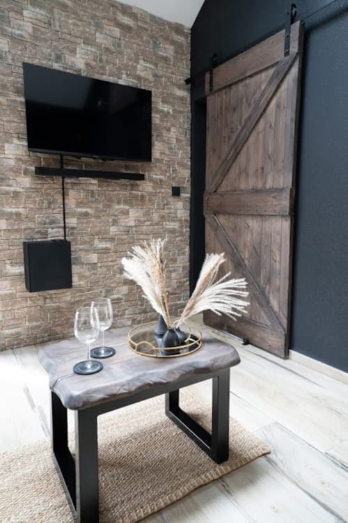 Intérieur cottage moderne à Accolade : murs en brique, TV écran plat, porte grange bois et console stylisée avec herbe de la Pampa