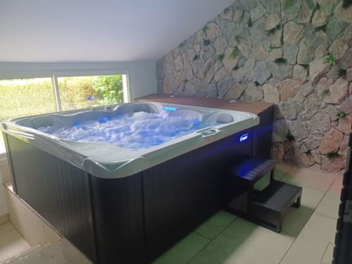 Bain à remous luxueux avec jets bleus dans un gîte aux murs de pierre à l'hôtel Accolade, Châteaudun, avec vue sur la rivière