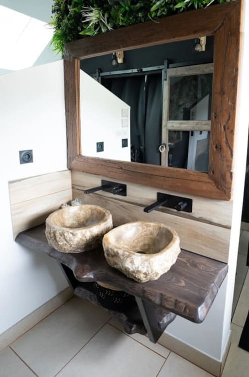 Vasque en pierre brute dans la salle de bain du cottage Accolade à Châteaudun, avec miroir à cadre bois et mur végétal vivant.