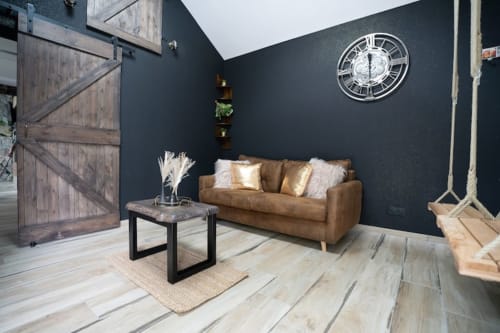 Salon moderne de cottage à l'hôtel Accolade à Châteaudun avec canapé en cuir beige, murs sombres et porte rustique en bois