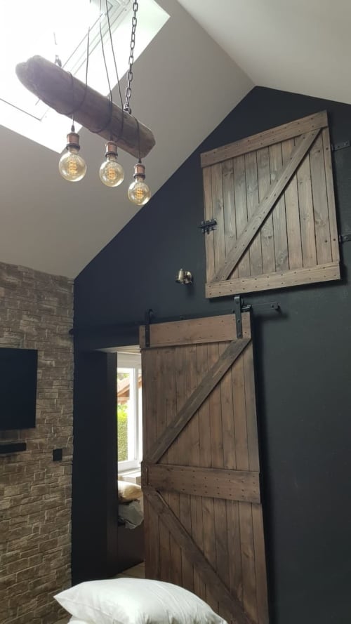 Chambre rustique moderne à Accolade avec portes de grange, luminaires suspendus industriels et murs de brique