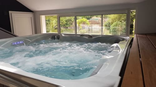 Baignoire de luxe avec jets et éclairage bleu à la Maison Accolade, Châteaudun, vue sur la rivière par les grandes fenêtres