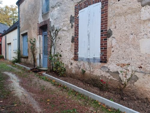 Chaumière de charme à Châteaudun avec façade en pierre patinée, volets bleus et jardin fleuri