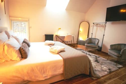 Chambre spacieuse de l'Hôtel Accolade à Châteaudun avec vue sur la ville, lit confortable, coin détente et équipements modernes