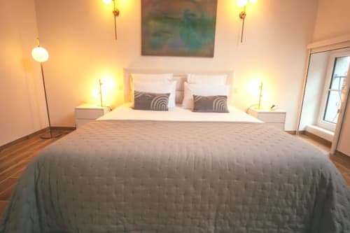Chambre moderne du gîte Accolade à Châteaudun avec lit queen-size, luminosité chaleureuse et vue sur la ville