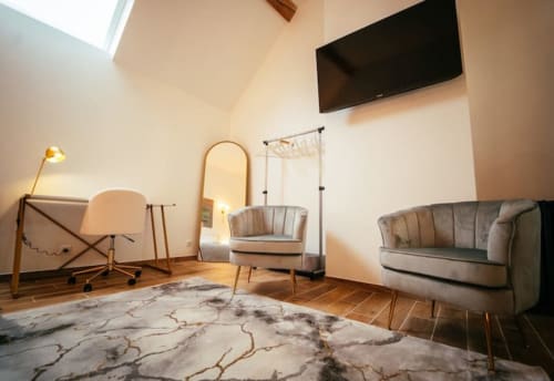 Salon contemporain du cottage Accolade à Châteaudun : sol en marbre, mobilier design, TV murale et vue sur la ville.