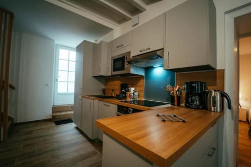 Cuisine cottage moderne à Accolade Châteaudun avec plans de travail en bois, armoires crème, dosseret bleu et acier inoxydable