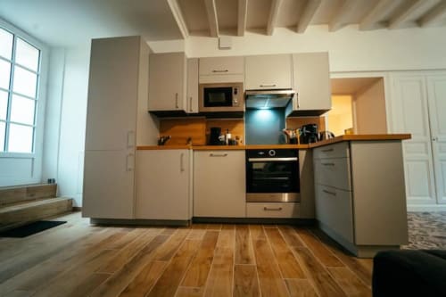 Cuisine moderne du gîte Accolade à Châteaudun, avec meubles beige, plans de travail en bois et électroménagers inox
