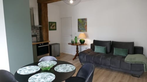Appartement moderne à Accolade à Châteaudun avec table à manger, canapé noir, kitchenette et décor chaleureux