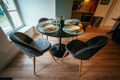Espace de salle à manger moderne à l'appartement Accolade à Châteaudun avec table ronde noire, chaises courbes, couverts et ouvert