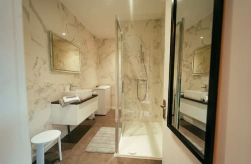 Salle de bain moderne de l'appartement Accolade à Châteaudun avec carrelage en marbre, douche à l'italienne, vasque et toilettes