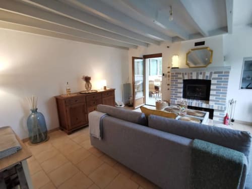 Salon douillet du gîte Accolade Châteaudun avec cheminée, canapé gris, mobilier en bois et vue sur le jardin