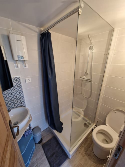 Salle de bain moderne du gîte Accolade à Châteaudun, avec douche, toilettes et carrelage blanc