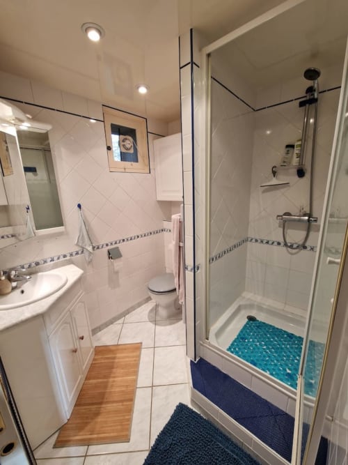 Salle de bain moderne du cottage Accolade à Châteaudun avec douche à l'italienne, carrelage blanc et vue sur le jardin
