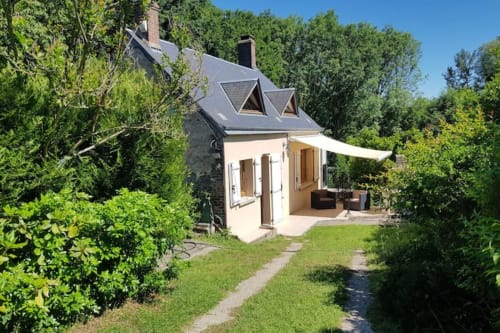 Cottage Accolade à Châteaudun, façade crème, toiture ardoise, terrasse aménagée avec auvent, entouré de verdure luxuriante