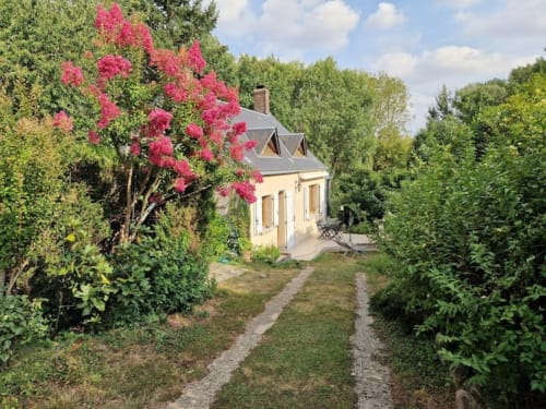 Adorable petite maison jaune à Châteaudun avec arbre fleuri rose, allée de jardin et haies luxuriantes