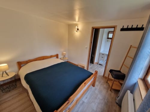 Chambre cosy du Cozy cottage à l'hôtel Accolade de Châteaudun avec lit en bois, linge de lit bleu marine et vue sur le jardin