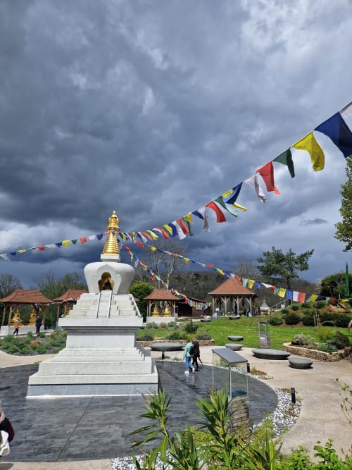 Stupa bouddhiste blanc aux toits dorés et drapeaux à prières colorés à Maisonaurinko à Thénon, France