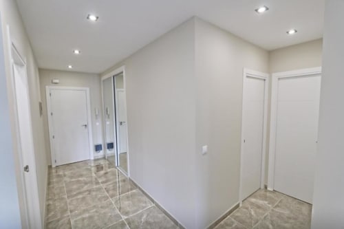 Pasillo moderno con puertas blancas y suelo de baldosa en apartamento frente al mar en Marbella