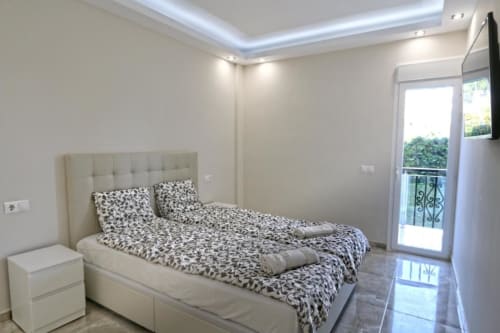 Dormitorio moderno de apartamento frente al mar en Puerto Banús, Marbella con cama tapizada crema y acceso a balcón