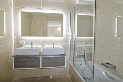 Baño moderno en apartamento frente al mar en Marbella con lavamanos doble, espejo iluminado y ducha de lujo
