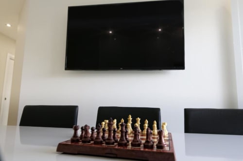 Moderno salón con televisor mural y juego de ajedrez en mesa, apartamento en primera línea de playa Marbella