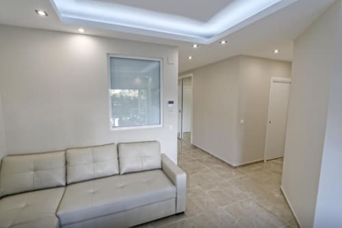 Sala de estar de apartamento frente al mar con sofá crema, piso de baldosas y luz natural en Puerto Banús, Marbella