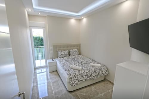 Moderno dormitorio en apartamento frente al mar de Marbella con cama doble, televisor de pantalla plana, acceso a balcón y vistas al jardín