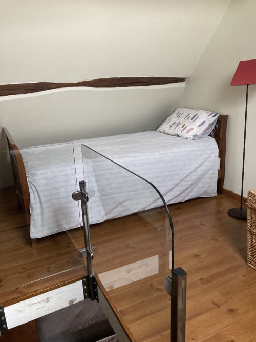 Cozy bedroom at Le Fassardy B&B in Châteauroux with wooden bed, light bedding, and red lamp under sloped ceiling