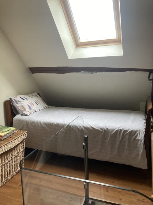 Cozy attic bedroom at Le Fassardy BnB in Châteauroux with skylight, white bedding, and wooden floors