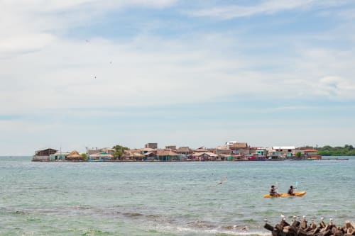 Casas de colores sobre pilotes junto a aguas turquesas del Caribe con kayakistas en Olamar Living, Santiago de Tolú, Colombia