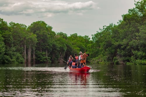 Bote rojo con turistas navegando bosques de manglares cerca del hotel Olamar Living en Santiago de Tolú, Sucre, Colombia