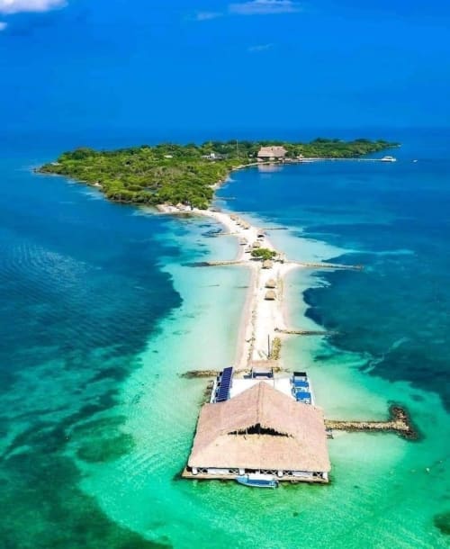 Vista aérea del resort Olamar Living con bungalós sobre el agua, playa pristina e isla exuberante en Coveñas, Colombia